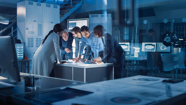 Reunião de Engenheiros em Laboratório de Pesquisa Tecnológica: Engenheiros, Cientistas e Desenvolvedores Reunidos em torno da Mesa de Conferências Iluminada, Solução de Conversação e Pesquisa, Inspeção e Análise — Fotografia de Stock