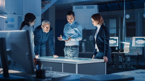 Professionals Meeting in Virtual Reality Content Design Creative Lab: Engineers, Scientists and Game App Developers Gathered Around Illuminated Interactive Table. Specialists Talking, Gesticulating