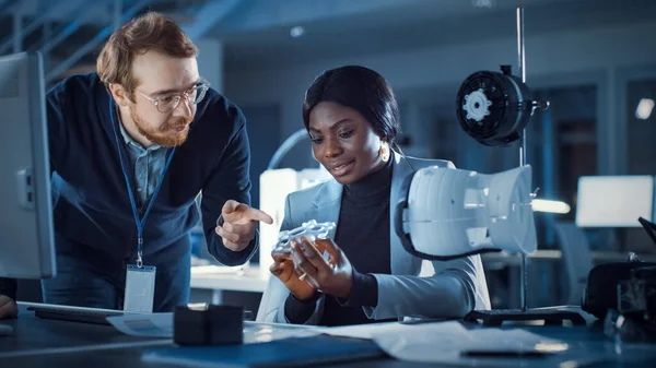 Engenheiro de Desenvolvimento Eletrônico Trabalhando em sua mesa, Fala com o gerente de projeto, Mostra Mecanismo Protótipo de Construção. Equipe de Profissionais que Trabalham na Agência de Projetos de Tecnologia Moderna. — Fotografia de Stock