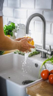 Bir Kişinin Yakın Çekimi Sarı Tatlı Biber 'i musluk suyuyla yıkıyor. Sağlıklı sebzeli otantik stil mutfak. Organik Tarım 'dan Doğal Temiz Ürünler Elle Yıkandı.