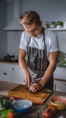 Beyaz Gömlekli ve Önlüklü Yakışıklı Modern Sunny Kitchen 'da Sağlıklı Organik Salata Yemekleri Yapıyor. Gözlüklü hippi aşçı. Doğal Temiz Diyet ve Sağlıklı Yaşam Konsepti.
