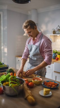 Pembe Gömlekli Yakışıklı Adam ve Önlüklü Modern Sunny Kitchen 'da Sağlıklı Organik Salata Yemekleri Yapıyor. Gözlüklü hippi. Doğal Temiz Diyet ve Sağlıklı Yaşam Konsepti.