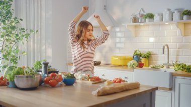 Modern Sunny Kitchen 'da Sağlıklı Organik Salata Yemekleri Hazırlayan Güzel Genç Kadın. O Mutlu ve Müzikle Dans Ediyor. Doğal Temiz Diyet ve Sağlıklı Yaşam Konsepti.