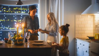 Mutfakta yemek hazırlayan ve servis yapan çok nesilli güzel kadınlar. Büyükanne, Kız ve Tatlı Küçük Torun Eğleniyor, Birlikte Yemek Yapıyor, Konuşuyor, Sırlarını Paylaşıyor ve Yemek Pişiriyor