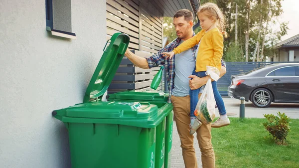 Father Holding a Young Girl and Throw Away an Empty Bottle and Food Waste into the Trash. They Use Correct Garbage Bins Because This Family is Sorting Waste and Helping the Environment. — Stock Photo, Image