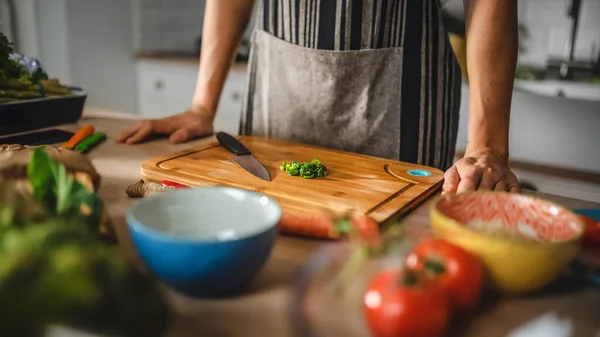 近距离拍摄一个人和一个切碎的绿色弹簧洋葱在一个切割板。在现代厨房里准备健康的有机沙拉.自然清洁饮食与健康生活方式概念. — 图库照片