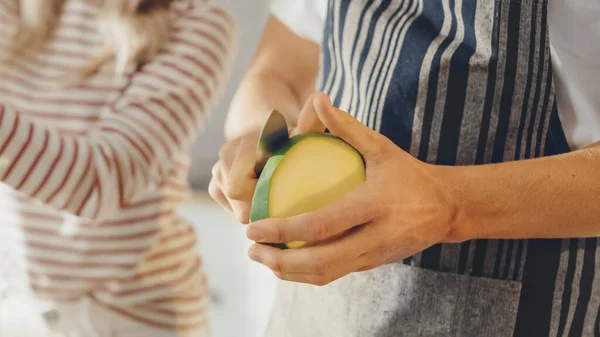 シャープなキッチンナイフでマンゴーを切る男のショットを閉じます。ヘルシーな野菜と本格的なスタイリッシュなキッチン。手作業で調製有機農業からの天然クリーン製品. — ストック写真