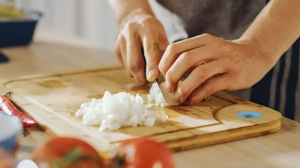 Nahaufnahme eines Mannes, der mit einem scharfen Küchenmesser eine Zwiebel zerhackt. Die Zubereitung einer gesunden biologischen Mahlzeit in einer modernen Küche. Natürliche saubere Ernährung und gesunder Lebensstil. — Stockfoto