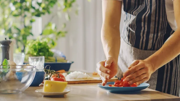 Nahaufnahme eines Mannes, der eine gehackte Tomate in eine Schüssel legt. Zubereitung einer gesunden vegetarischen Bio-Salatmahlzeit in einer modernen Küche. Natürliche saubere Ernährung und gesunder Lebensstil. — Stockfoto