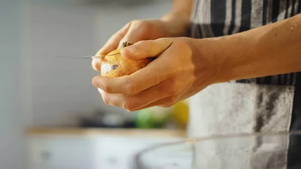 Nahaufnahme eines Mannes, der mit einem scharfen Küchenmesser einen Granatapfel schneidet. Die Zubereitung eines gesunden veganen Bio-Snacks in einer modernen Küche. Natürliche saubere Ernährung und gesunder Lebensstil. — Stockfoto