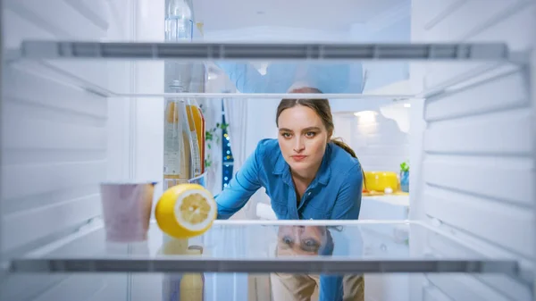 Desapontado e irritado jovem mulher olha para dentro da geladeira, Verifica que o seu Empy. Ponto de vista POV de dentro da geladeira da cozinha — Fotografia de Stock