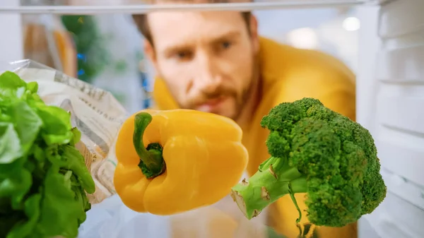 Camera Inside Kitchen Frigorífico: Homem bonito abre a porta do frigorífico, olha para brócolis fresco, pimentão do sino. Homem Preparando Salada Saudável. Ponto de vista POV tiro da geladeira cheia de alimentos saudáveis — Fotografia de Stock