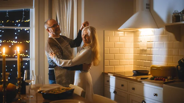 Senior Couple i Love Have Romantic Evening, Dancing in the Kitchen, Celebrating Anniversary (engelsk). Romantisk kveld med vin, festlig bord i kjøkken og kjøkken. – stockfoto