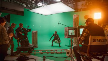 Büyük Film Stüdyosunda Profesyonel Ekip Çekimi Blockbuster Film. Yönetmen Kameraman 'a Yeşil Ekran CGI Sahnesi' ni Aktör Hareketi Yakalayıcı Takım Elbisesi ve Başlık Takımlı Çekmeye Başlaması Emretti