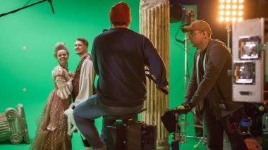 Film Stüdyosunda Tarih Filmi Çekimi Yeşil Ekran Sahnesi. Demiryolu Tramvayındaki Kameraman, Yönetmen Süreç 'i Denetlerken İki Kostümlü Aktör Çekiyor. Büyük Bütçe Film Yapımcılığında Profesyonel Ekip 