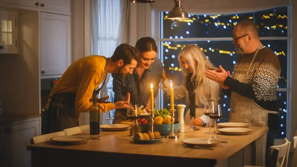 Happy Family of Celebrating samen, zitten aan de tafel met heerlijk diner. Jonge moeder neemt schotel uit Oven Grootouders Bewonder hoe heerlijk ovenschotel eruit ziet — Stockfoto