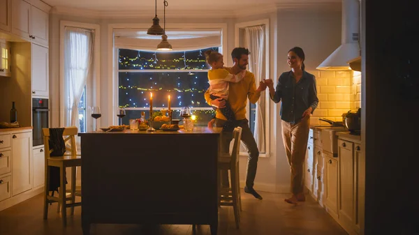 Buona famiglia di tre che si divertono dopo cena a ballare insieme. Padre forte tiene e abbraccia la piccola figlia carina, ballano insieme alla bella giovane madre. Accogliente celebrazione serale — Foto Stock