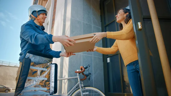 Happy Food Delivery Homme portant un sac à dos thermique sur un vélo livre la commande de pizza à une belle cliente. Courier livre de la restauration rapide à emporter à une fille souriante dans un immeuble de bureaux. Angle bas — Photo