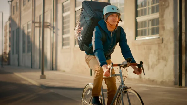 Happy Food Delivery Courier Usar Mochila Térmica Monta uma Bicicleta na Estrada Para Entregar Encomendas para Clientes e Clientes. Dia ensolarado no bairro da cidade moderna. — Fotografia de Stock