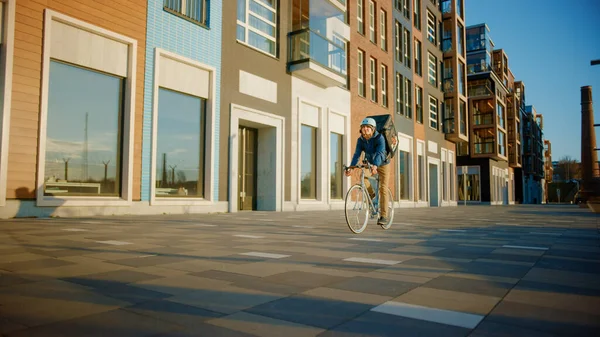 快乐食品快递员穿着保暖背包骑着自行车为顾客运送订单和包装。古色古香的城市里的艳阳天. — 图库照片