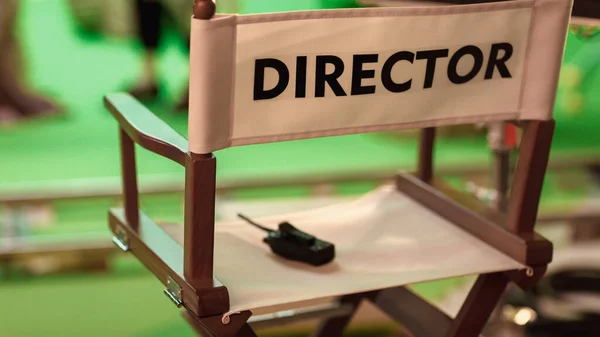 Στο στούντιο κινηματογράφησης Κοντινό πλάνο του Empty Directors Chair. Στο παρασκήνιο Professional Πλήρωμα γυρίσματα πράσινη οθόνη σκηνή με ηθοποιούς για την ιστορία ταινία. — Φωτογραφία Αρχείου