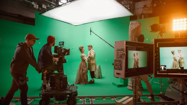 On Set: Berömda kvinnliga regissören kontrollerar kameraman skytte grön skärm scen med två skådespelare begåvade bär renässans kläder talar. Besättning Shooting Period Kostym Drama Movie. — Stockfoto