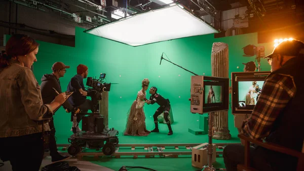 Στο Big Film Studio Professional Πλήρωμα γυρίσματα ιστορία κοστούμι Δράμα ταινία. Στο σετ: Σκηνοθεσία πράσινη σκηνή με όμορφη κυρία φορώντας αναγεννησιακή φορεσιά συναντά τον ηθοποιό παίζοντας τέρας — Φωτογραφία Αρχείου