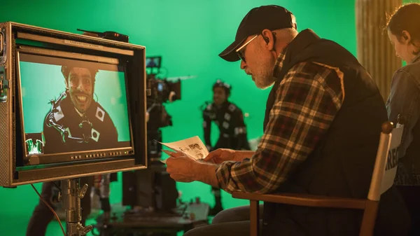 Director mira la pantalla y se compara con Storyboard mientras filma Blockbuster Movie. Escena de pantalla verde con el actor que lleva traje de leyenda de movimiento. Film Studio Professional Crew Haciendo películas de alto presupuesto — Foto de Stock