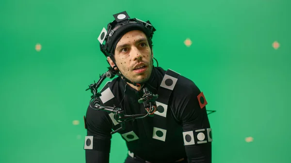 Portrait of an Actor Wears Motion Caption Suit and Head Rig Posing with Green Screen Background (англійською). Big Budget Filmmaking On Film Studio Set Shooting Blockbuster Movie with Chroma Key. — стокове фото