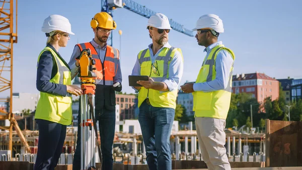 Diverse Team of Specialists Use Tablet Computer on Construction Site. Real Estate Building Project with Civil Engineer, Architect, Business Investor and Surveyor with Theodolite Discussing Plans. — Stock Photo, Image