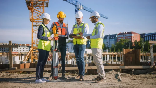 Diverse Team of Specialists Use Tablet Computer on Construction Site. Real Estate Building Project with Civil Engineer, Architect, Business Investor and Surveyor with Theodolite Discussing Plan. — Stock fotografie