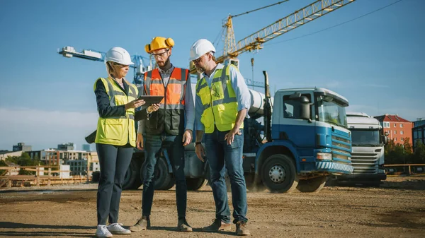 Diversos equipos de especialistas utilizan Tablet Computer en el sitio de construcción. Proyecto de construcción inmobiliaria con Ingeniero Civil, Arquitecto, Inversor de Negocios Discutiendo detalles de planificación y desarrollo. — Foto de Stock