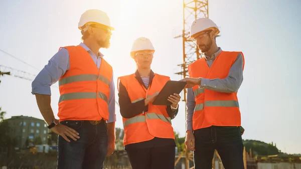 Team av specialister använder Tablet Computer på byggarbetsplatsen. Fastighetsbyggnadsprojekt med civilingenjör, arkitekt, affärsinvesterare Diskutera planering och utveckling Detaljer. Soleruption. — Stockfoto