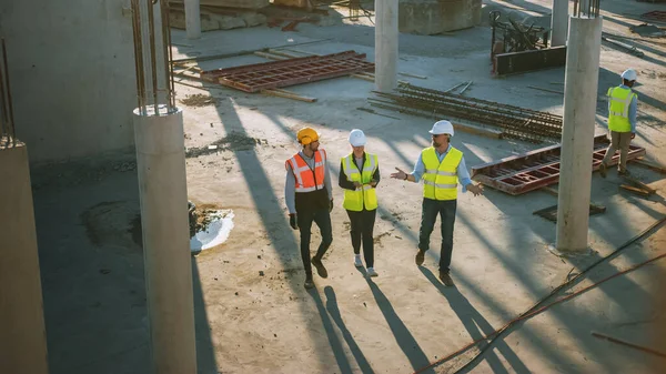 Equipe diversificada de especialistas dando um passeio através do canteiro de obras. Projeto de Construção Imobiliário com Engenheiro Civil Sênior, Arquiteto, Trabalhador Geral Discutindo Planejamento e Desenvolvimento Detalhes. — Fotografia de Stock