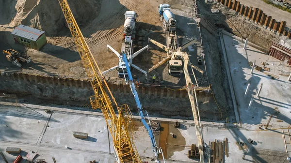 Aerial Shot of a New Constructions Development Site with High Tower Cranes Building Real Estate and Concrete Mixer Trucks. Maquinaria pesada y construcción. Vista de arriba hacia abajo en los contratistas en sombreros de seguridad — Foto de Stock