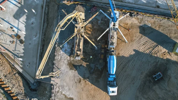 Aerial Shot of a New Constructions Development Site with Concrete Mixer Trucks Building Real Estate. Maquinaria pesada y construcción. Vista de arriba hacia abajo en los contratistas en sombreros de seguridad — Foto de Stock