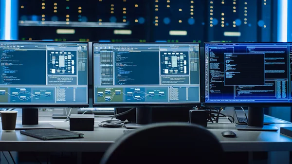 Aufnahme von mehreren Personal Computer Monitoren, die Programmiersprache mit System Monitoring Interface zeigen. Im Hintergrund Rechenzentrum mit Server-Racks. — Stockfoto