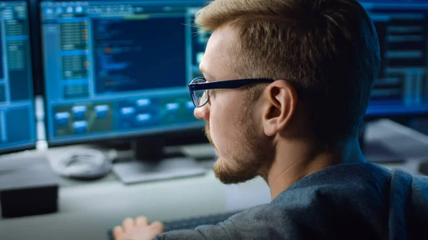 Especialista en TI trabaja en computadora personal con pantallas que muestran el programa de software con interfaz de lenguaje de codificación. En la sala técnica de fondo del centro de datos con trabajo profesional —  Fotos de Stock