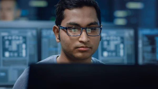 Portret inteligentnego i przystojnego specjalisty IT pracującego na komputerze osobistym. W tle Bokeh Shot komputerów osobistych z ekranami w technologicznie zaawansowanym centrum badań danych — Zdjęcie stockowe
