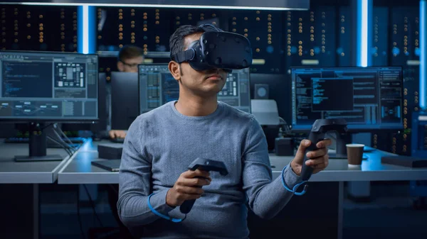 Software Delevoper Wearing Virtual Reality Headset Using Controllers to Develop and Program VR Gaming Applications 의 모델이다. 배경 기술 개발 스튜디오에서 컴퓨터와 모니터로 — 스톡 사진