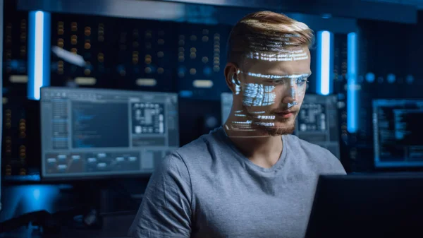 Młody programista pracujący na komputerze osobistym w Centrum Danych Cyberbezpieczeństwa, projektowany język kodowania programu odzwierciedla jego twarz. Futurystyczna koncepcja hakowania i programowania — Zdjęcie stockowe