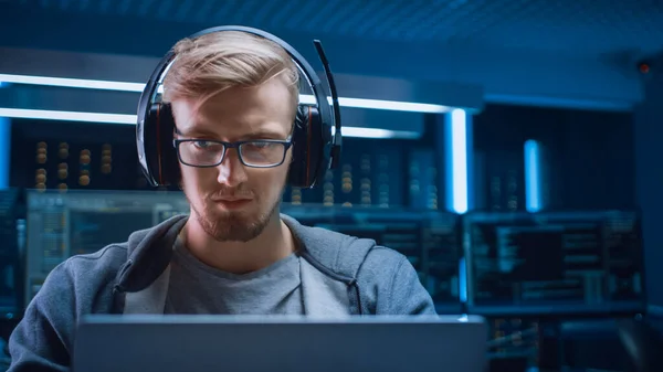 소프트웨어 개발자 해 커 게이머의 초상화 Wearing Glasses and Headset Sitting at His Desk and Working Playing on Laptop. 배경검은 네온 첨단 기술 환경의 다양 한 디스플레이. — 스톡 사진