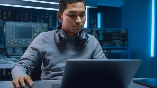 Retrato do programador de software Hacker Programador sentado em sua mesa e trabalhando no computador portátil no fundo escuro Neon ambiente de alta tecnologia com várias exposições. — Fotografia de Stock