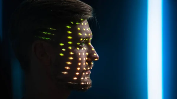 Jóképű fiatal kaukázusi férfit biometrikus arcfelismerő vizsgálattal azonosítanak. Futurisztikus koncepció: Projektor azonosítja az egyén megvilágító arc színes pontok és lézer — Stock Fotó