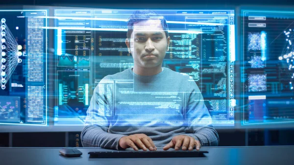 Портрет разработчика программного обеспечения хакера в очках, сидящего за своим столом и работающего на футуристическом прозрачном компьютере в центре данных цифровой идентификации кибербезопасности. Взлом или программирование. — стоковое фото