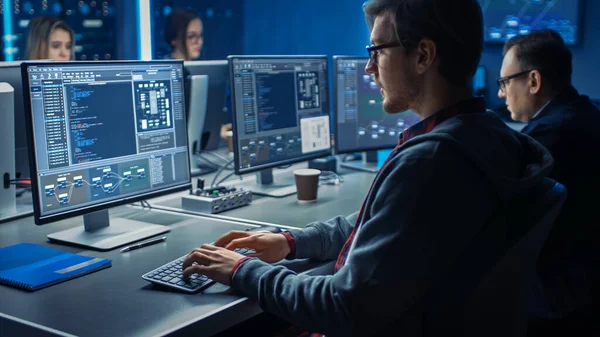 在数据中心系统控制室的桌上型绿色模拟屏幕计算机上工作的聪明男性IT程序员。青年专业人员小组编制复杂的代码 — 图库照片