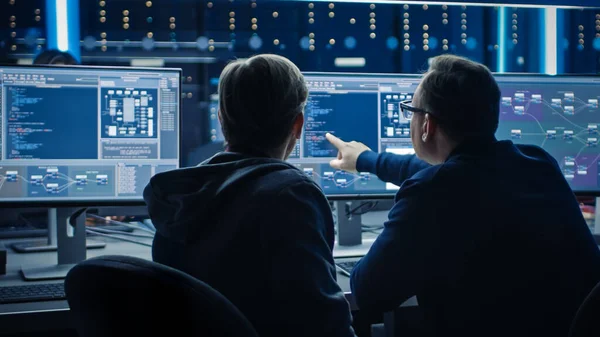 Dos programadores profesionales de TI discutiendo el diseño y desarrollo de la arquitectura de redes de datos Blockchain que se muestra en la pantalla de la computadora de escritorio. Departamento técnico del centro de datos de trabajo con bastidores del servidor —  Fotos de Stock