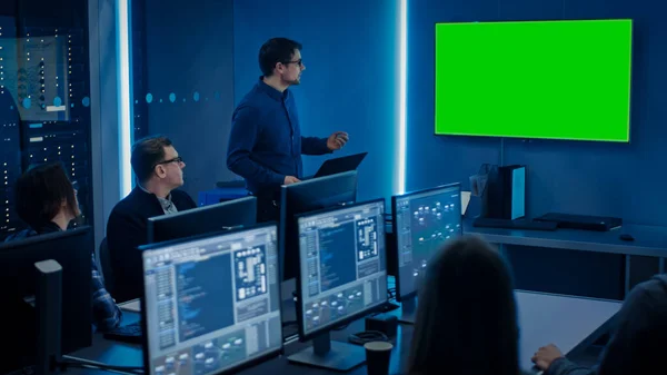 Team of Professional IT fejlesztők Van egy találkozó, Előadó beszél az új fogalmak, A Wall TV zöld Mock-up képernyő. Koncepció: Szoftverfejlesztés, Mélytanulás, Mesterséges Intelligencia — Stock Fotó