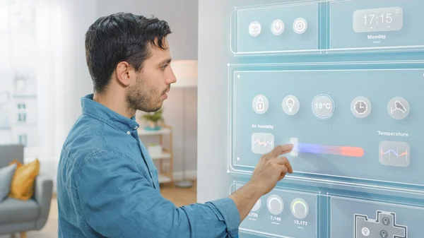 Un bel giovanotto si avvicina a un frigorifero. Sta cambiando temperatura sullo schermo intelligente del frigorifero a casa. La cucina è luminosa e accogliente. — Foto Stock