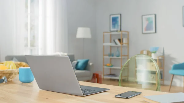 Opname van een moderne zilveren laptop op een houten tafel thuis. Smartphone Ligt op een tafel naast de computer. — Stockfoto